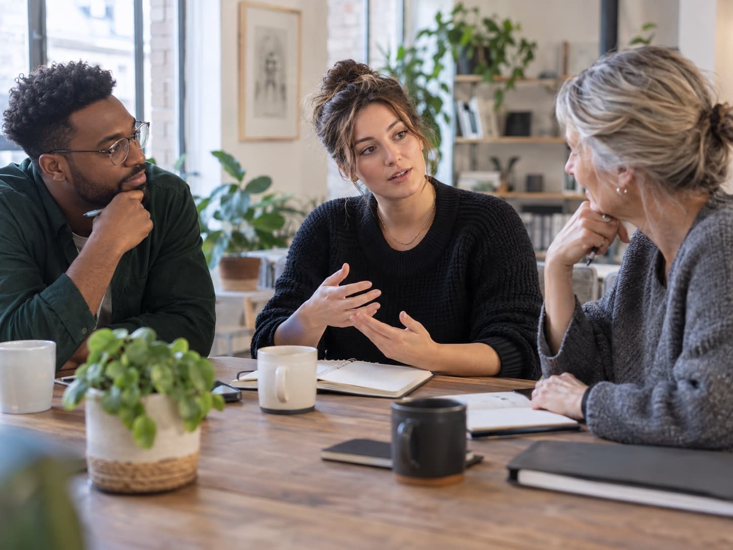 Three colleagues listening and talking together around a table